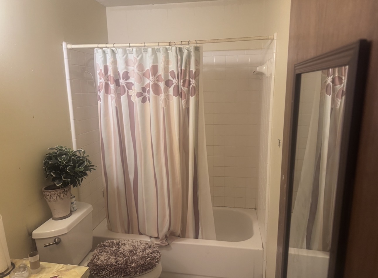 Dated bathroom with old tile tub surround before remodel