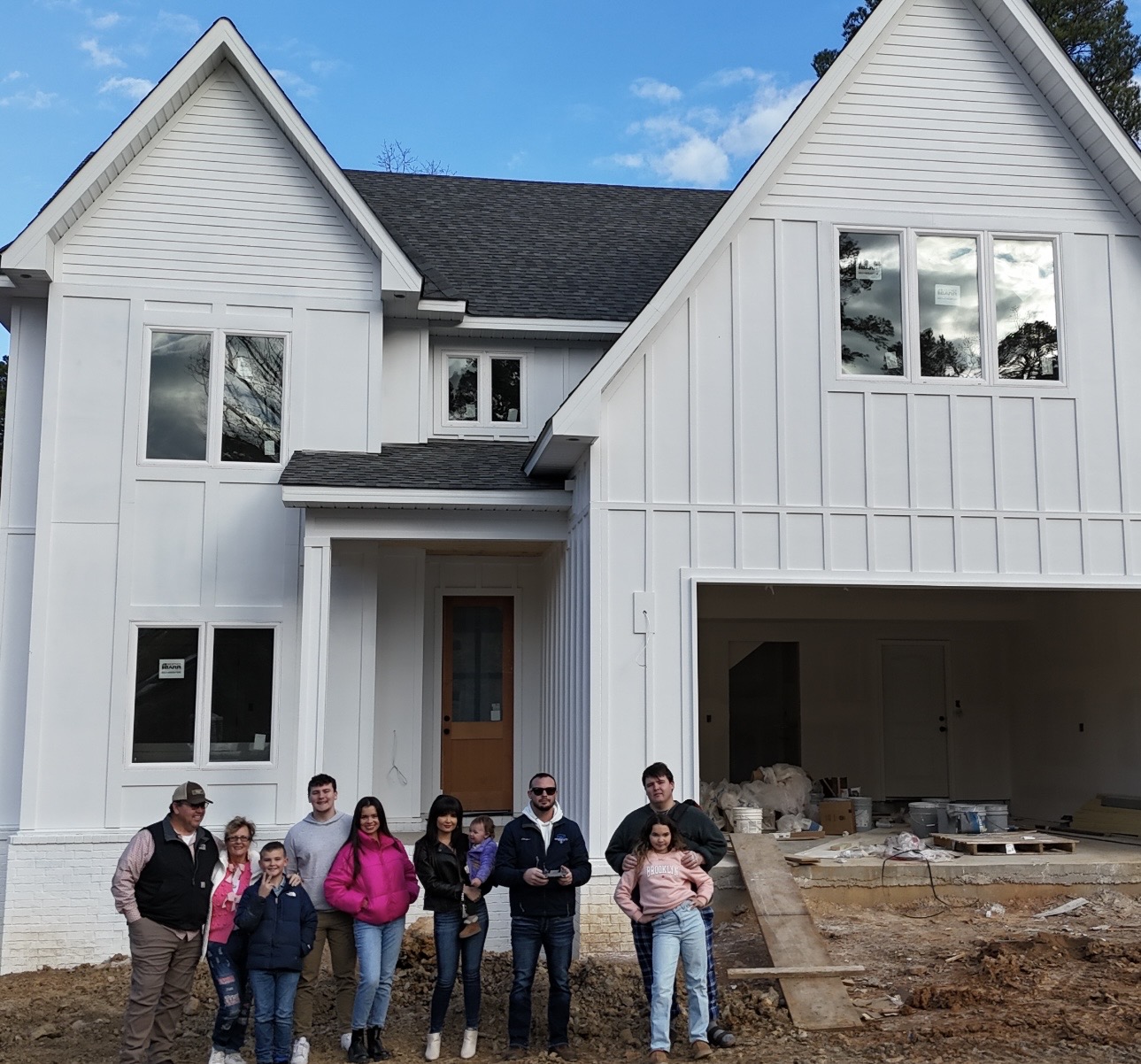 Family in front of a new construction home with board and batten siding