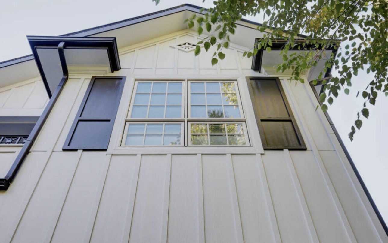 Close-up of board and batten fiber cement siding with black shutters and gutters