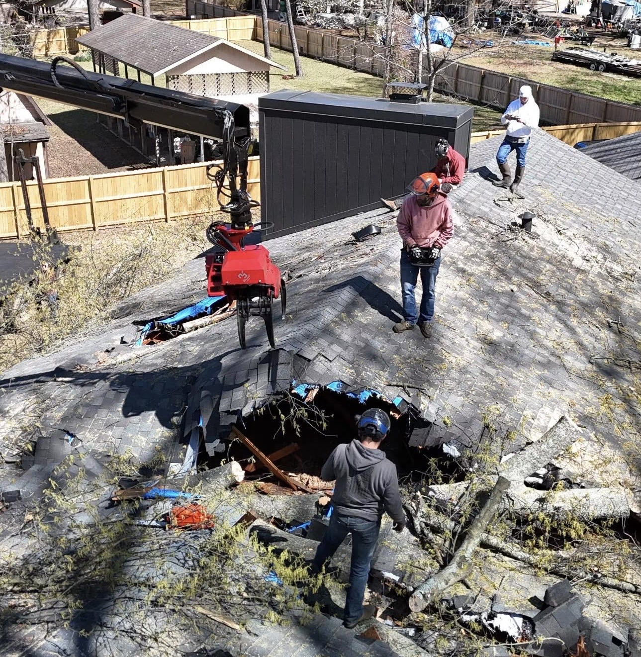 Crew working around a tree impact hole in a storm damaged roof
