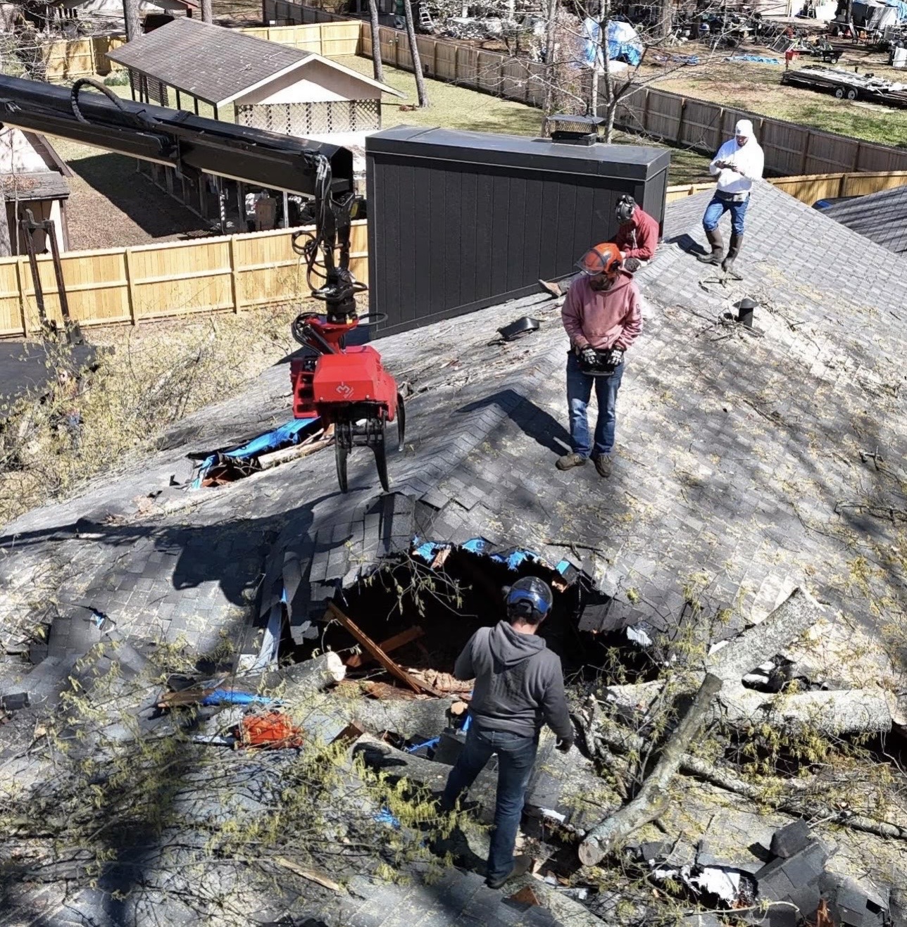 Tree impact on a Hensley roof with workers and equipment assessing the damage