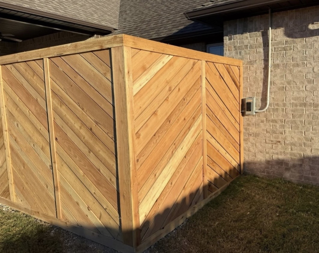 Custom chevron pattern cedar privacy screen beside a brick home