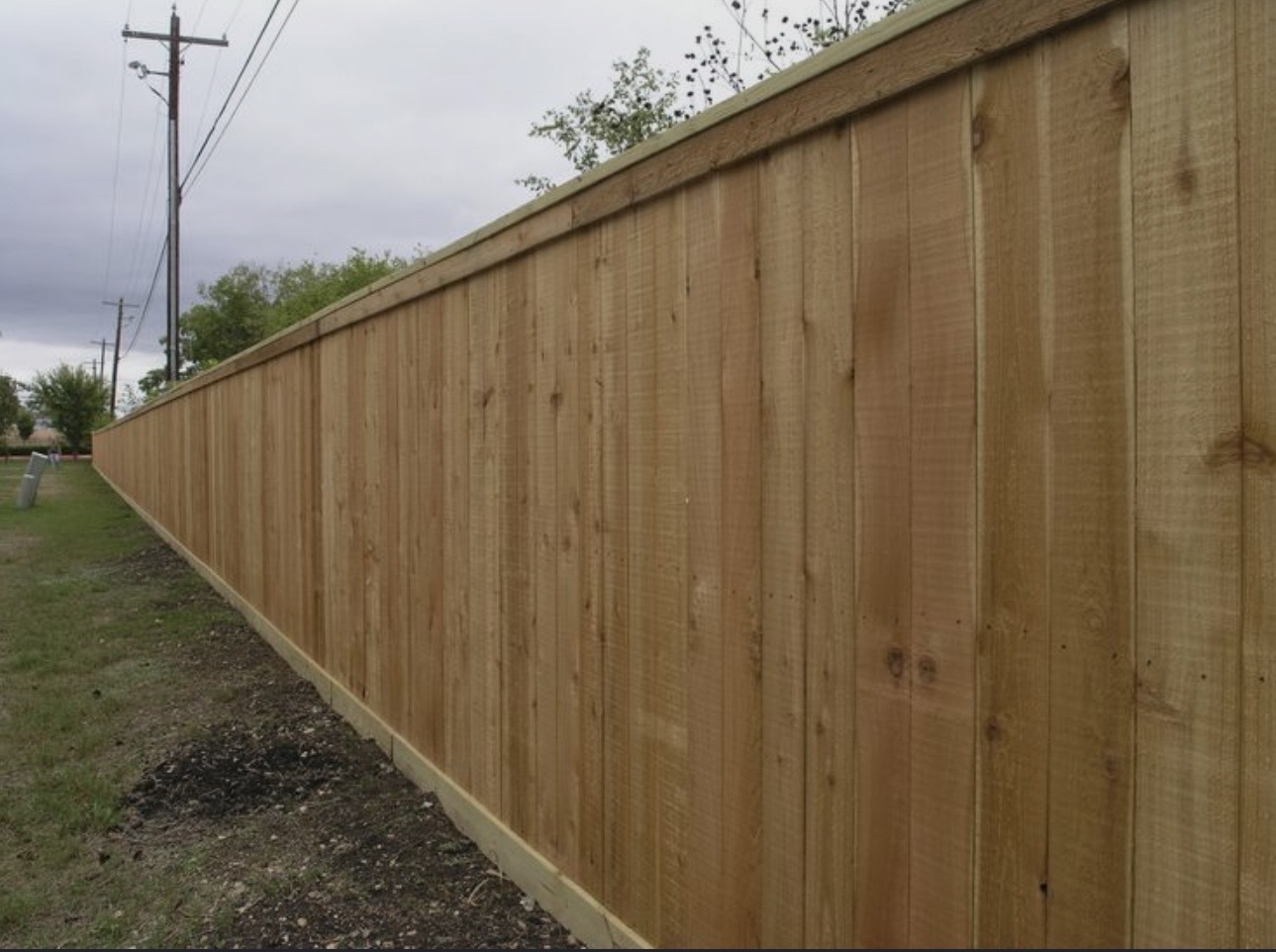 Long straight run of new treated pine privacy fence along a property line